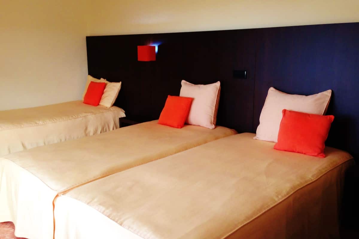 Two single beds with red and white pillows, a dark headboard, and a small red light fixture.