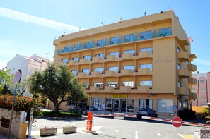Un hôtel à plusieurs étages doté de balcons, d’une entrée bien visible et d’un espace de stationnement.
