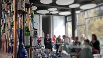 A bar area with bottles and glasses, a seating area with tables and chairs, and a view through large windows.