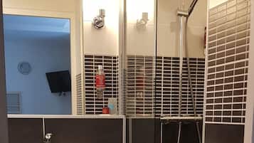 Ein modernes Badezimmer mit einem weißen Waschbecken, schwarzen Fliesenwänden und einer Duschkabine aus Glas.