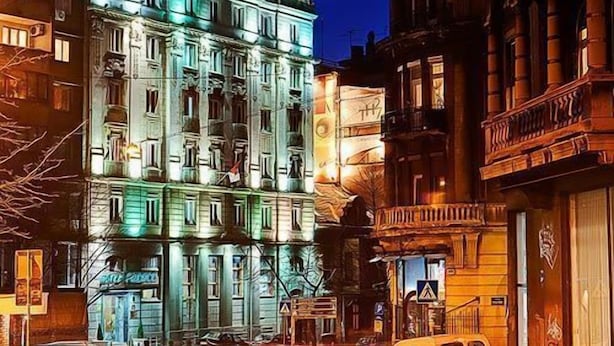 Et hotel med flere etager, et markant neon-skilt, store vinduer og en klassisk arkitektur.