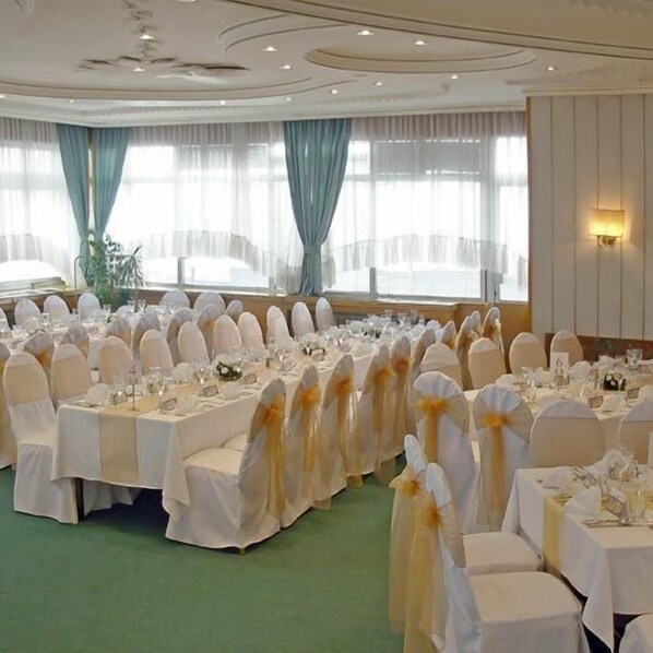 A banquet hall with round tables, white tablecloths, and chairs with yellow sashes. - Palace Hotel (Belgrade)
