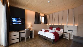 Una habitación de hotel moderna con techo de madera, un televisor de pantalla plana, un escritorio con silla, una cama con ropa de cama roja y una mesita de noche pequeña.