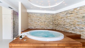 Un espace spa moderne doté d’un jacuzzi, d’un plancher en bois et d’un mur en mosaïque.