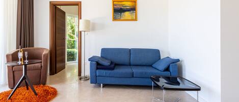 Una sala de estar moderna con un sofá azul, una mesita negra y un sillón marrón.