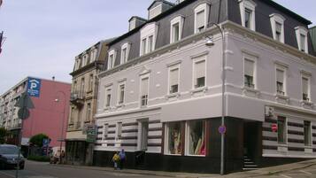 A multi-story building with a white facade, large windows, and a visible storefront.