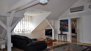 Un salon moderne de style industriel, avec un canapé noir, une table basse en bois et un grand tableau accroché au mur.