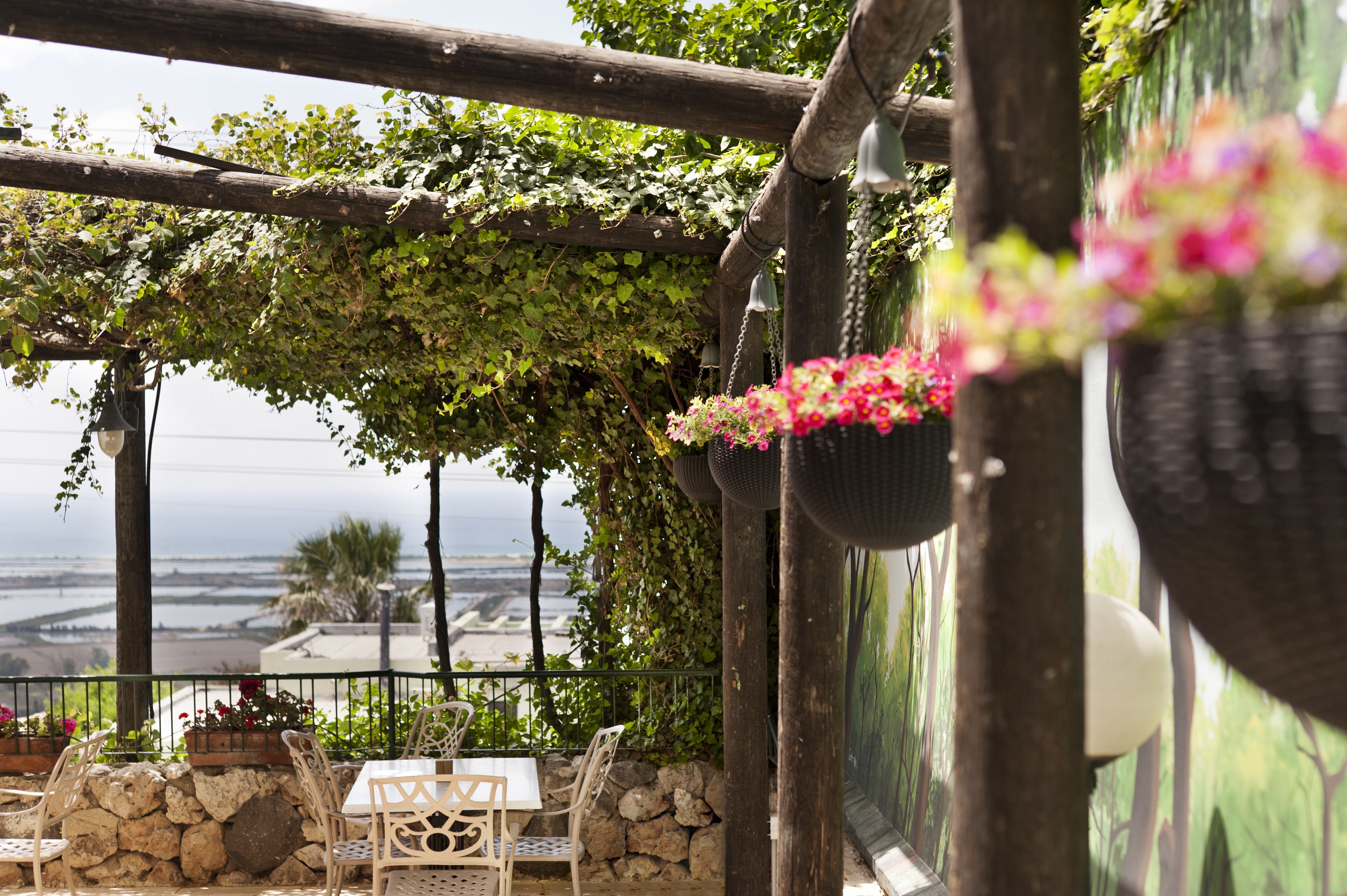A terrace with stone walls, wicker chairs, and hanging flower baskets.
