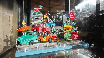 Une collection colorée de voitures miniatures et de figurines exposée sur une étagère.