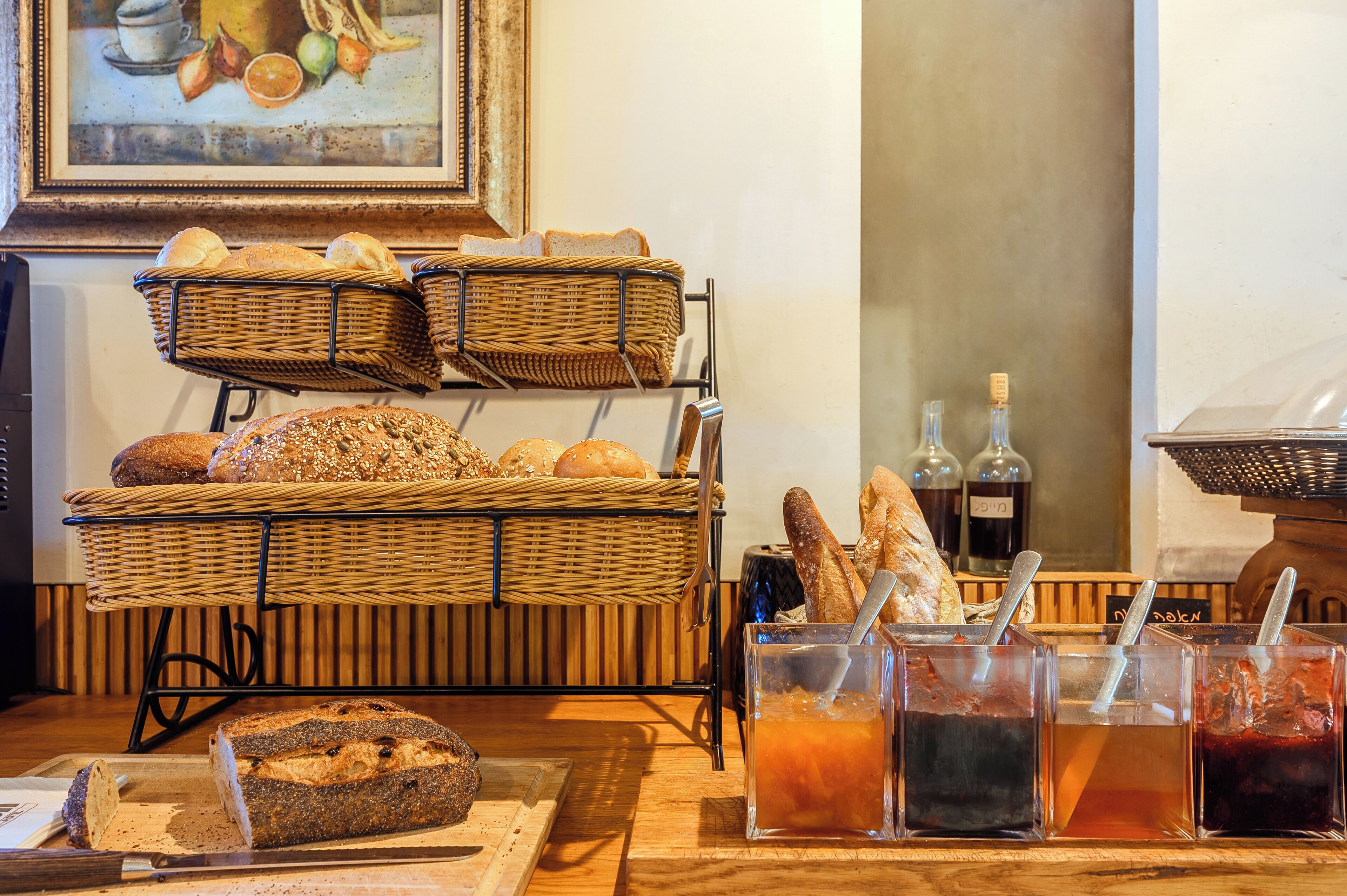 A breakfast buffet with various breads, pastries, and beverages.