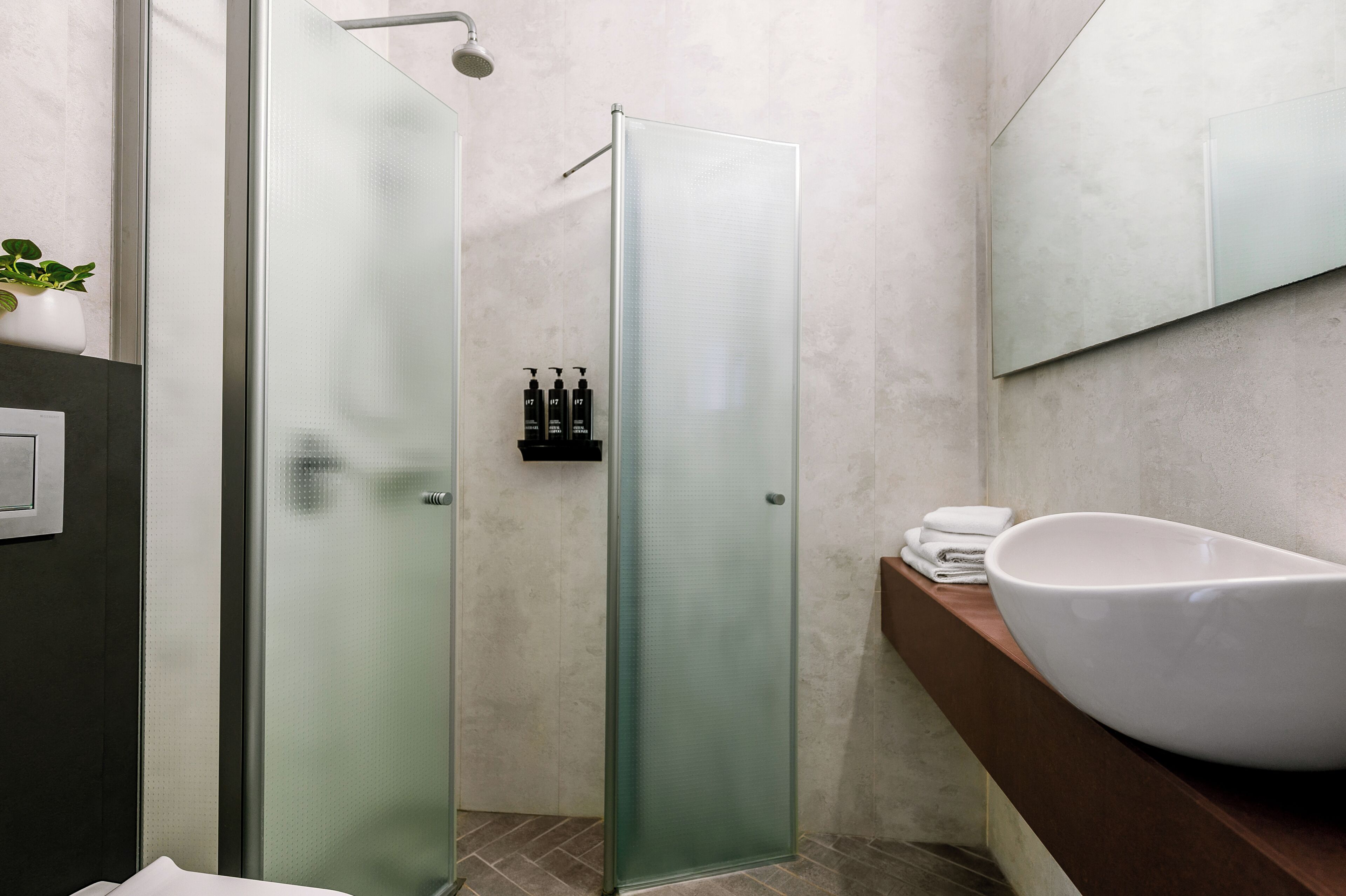 A modern bathroom with a glass-enclosed shower, a large white sink, and a mirror above the sink.
