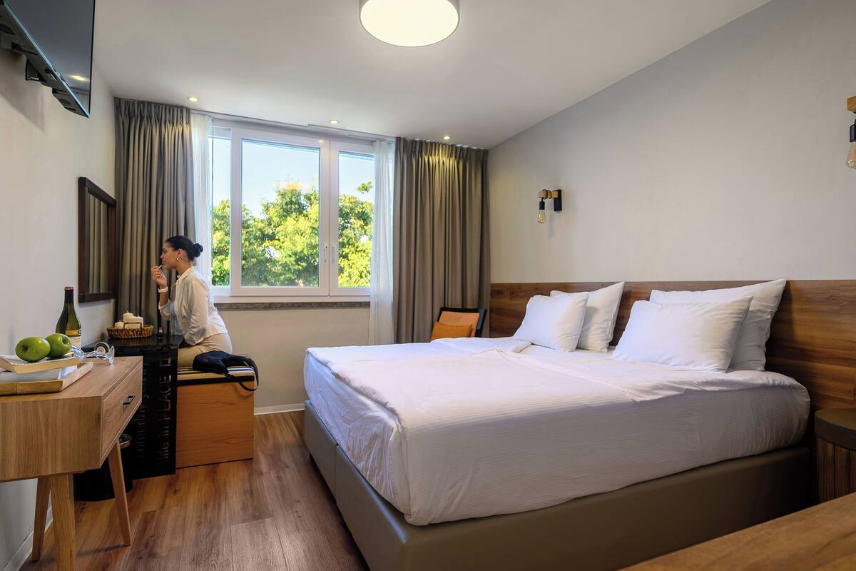 Una habitación de hotel moderna con una cama grande, un escritorio y una ventana con cortinas.