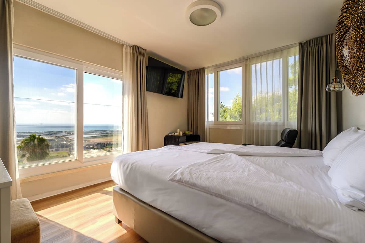 Habitación de hotel con una cama grande, televisor montado en la pared y vista al océano.