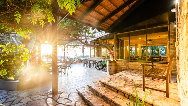 Un patio al aire libre con piso de piedra, bancos y mesas de madera.
