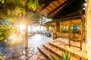 Un espace extérieur aménagé en terrasse, avec un sol en pierre, des bancs en bois et des tables.