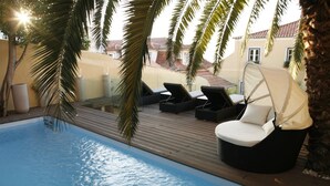 A poolside area with lounge chairs and a palm tree. - Palacio Ramalhete (Lisbon)