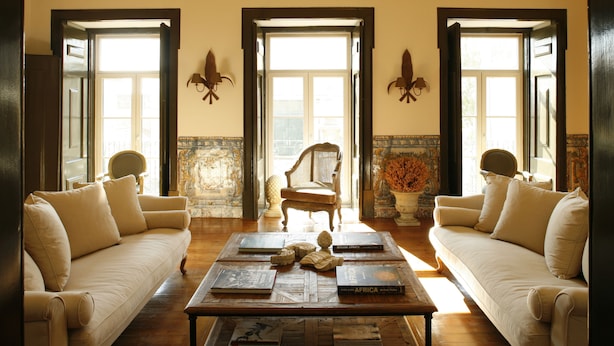 A room with two sofas, a coffee table with books, and a chair. - Palacio Ramalhete (Lisbon)