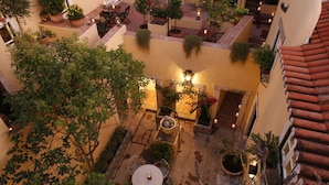 An outdoor courtyard with multiple seating areas, potted plants, and a central light fixture. - Palacio Ramalhete (Lisbon)