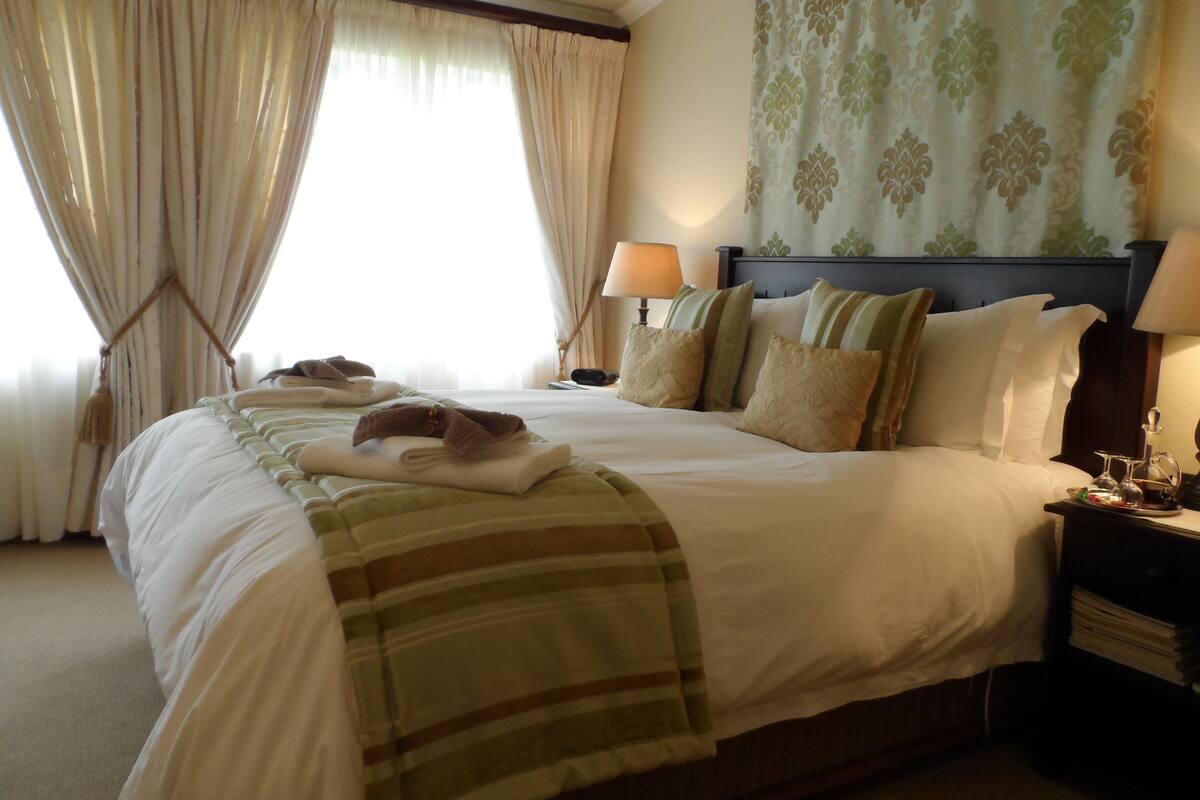 Una camera d'albergo con un letto grande, due comodini, una testiera e una finestra con tende.
