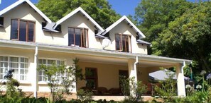 A two-story house with a covered porch, large windows, and a satellite dish. - Porcupine Ridge Guest House (Sabie)