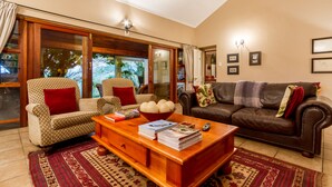 A living room with a sofa, armchairs, a coffee table, and a fireplace. - Porcupine Ridge Guest House (Sabie)