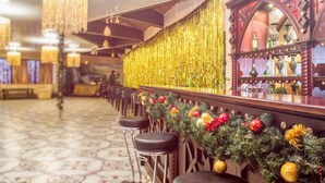 Una zona de bar con una barra alargada, varios taburetes y una guirnalda decorativa navideña.