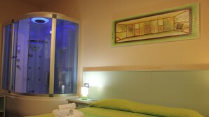 Una camera d'albergo con un letto, una poltrona massaggiante e un quadro appeso al muro.