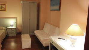 Una camera da letto con un letto, un comodino, un armadio, una panca, una scrivania e una lampada.