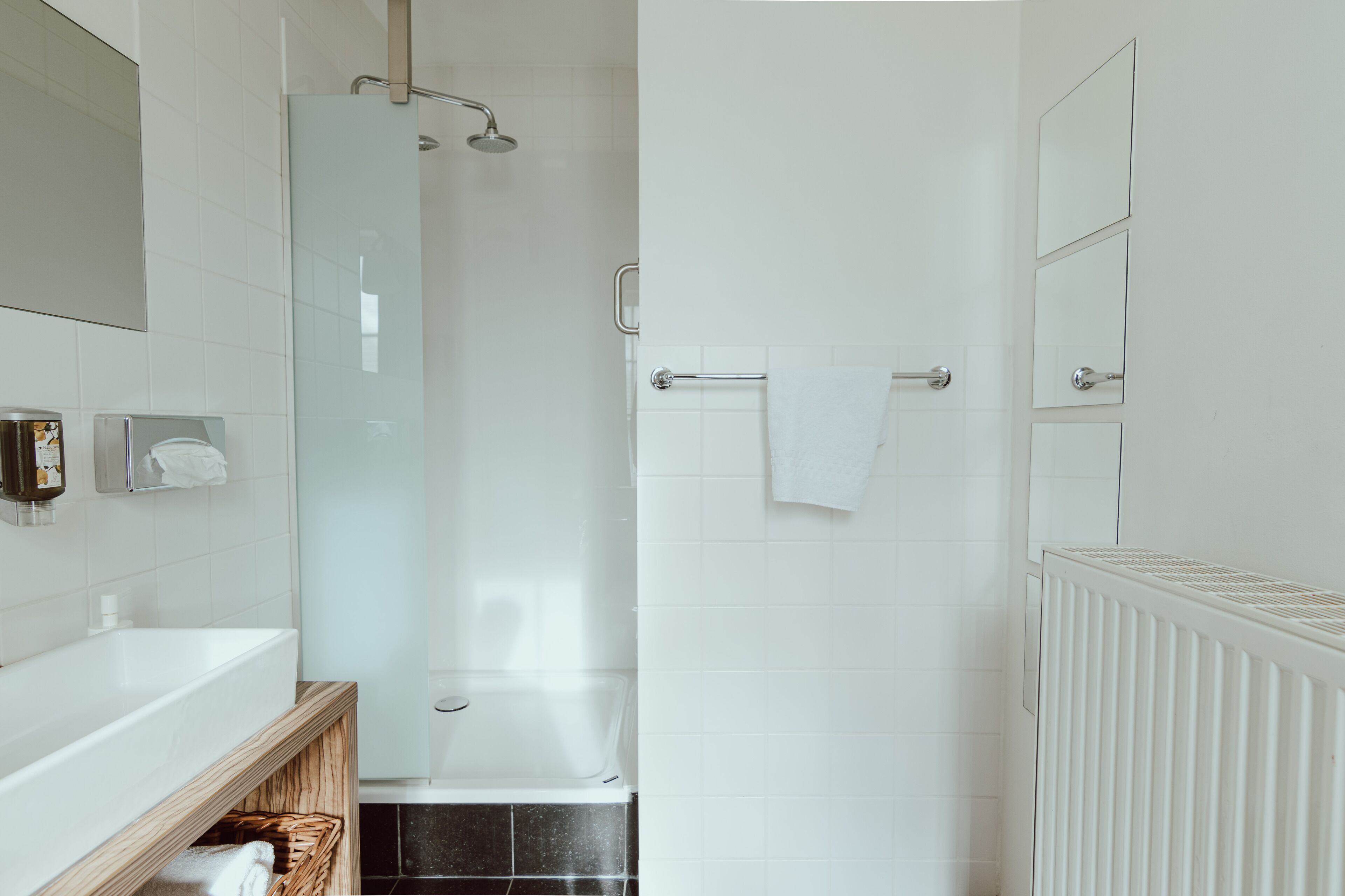 Ein modernes Badezimmer mit Duschkabine aus Glas, einer weißen Badewanne und einem Holzwaschtisch mit Handtuchhalter.