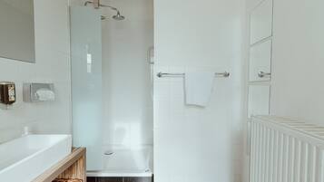 Ein modernes Badezimmer mit Duschkabine aus Glas, einer weißen Badewanne und einem Holzwaschtisch mit Handtuchhalter.
