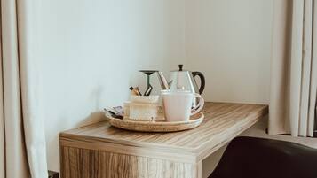 Ein kleiner Holztisch mit einem schwarzen Stuhl, einer weißen Tasse, einer weißen Kaffeetasse und einem kleinen Korb mit Gegenständen.