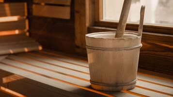 A wooden bucket with two handles on a wooden bench near a window.