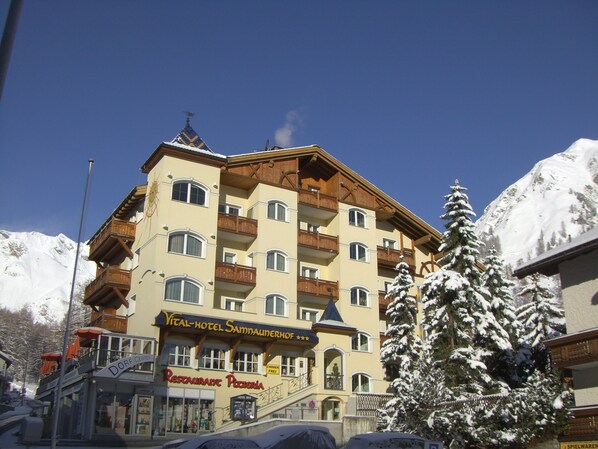 A multi-story hotel with a ski lift in the background, a restaurant named "Restaurante Pizzeria" on the ground floor, and snow-covered trees in front. - Samnaunerhof Vital-Hotel (Samnaun)