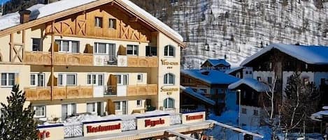 A hotel with a restaurant and outdoor seating area, surrounded by snow-covered mountains.