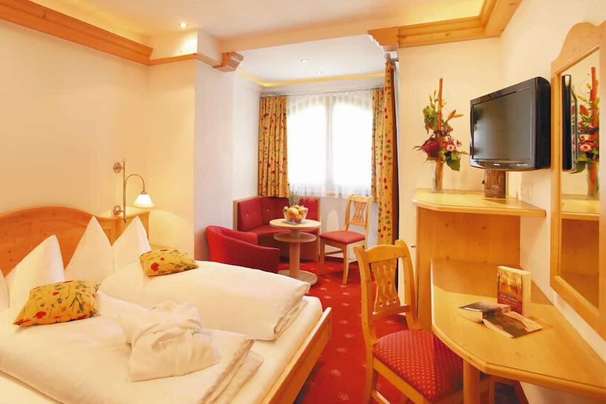 A hotel room with two beds, a TV, a small desk, and a chair.