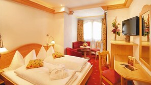 A hotel room with two beds, a TV, a small desk, and a chair. - Samnaunerhof Vital-Hotel (Samnaun)