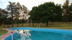 Una piscina con un borde de baldosas y una valla de madera al fondo.