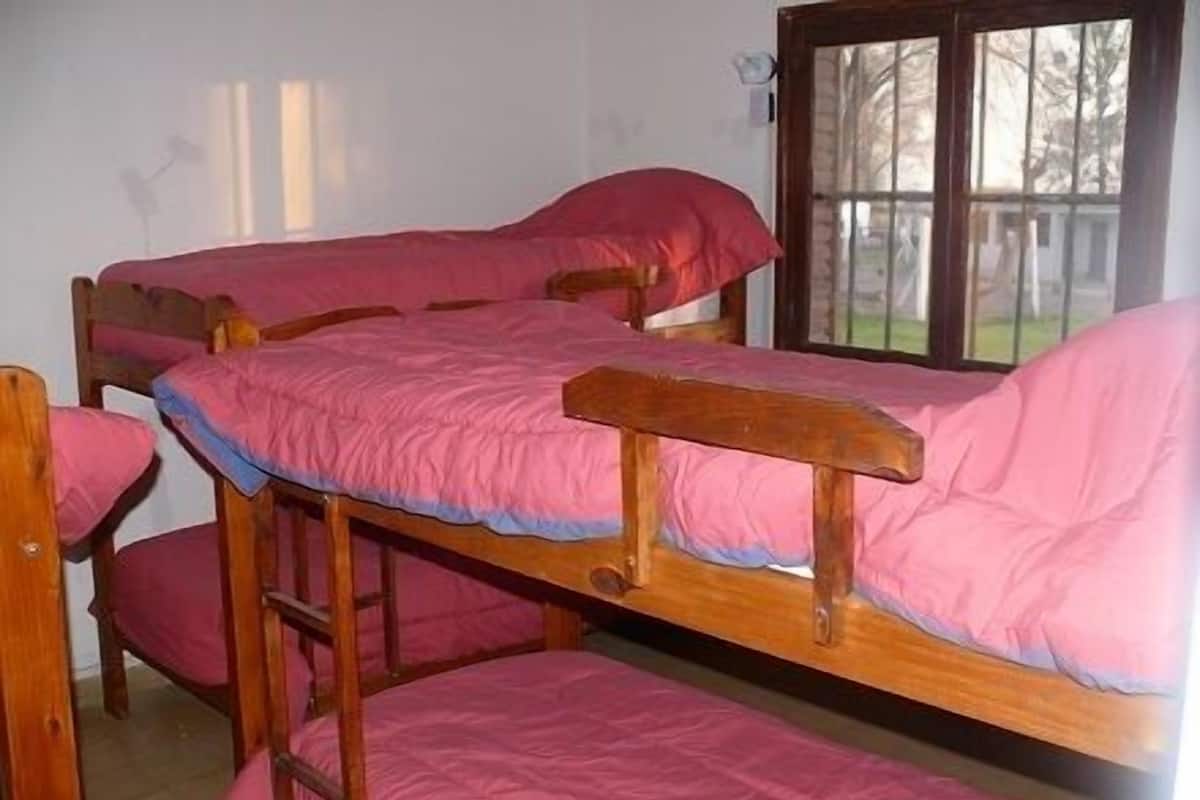 Habitación con literas, ropa de cama rosa y estructura de madera.