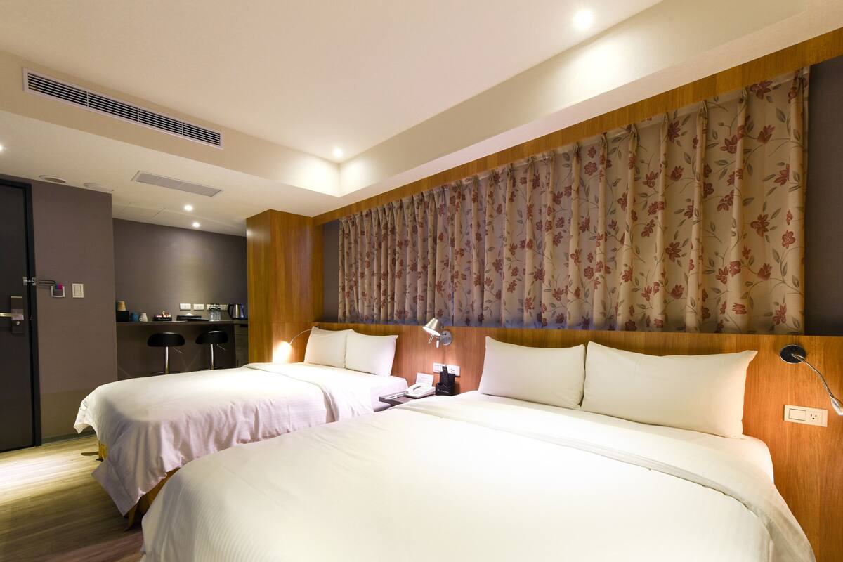 Ein Hotelzimmer mit zwei Betten, einer kleinen Küchenzeile und einem Badezimmer.