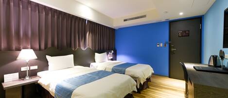 A hotel room with two beds, a desk, a lamp, and a door with a sign.