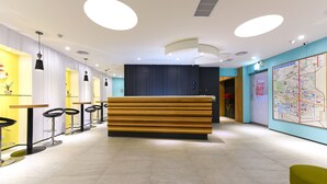 Ein moderner Empfangsbereich mit einem Holzbüro, schwarzen Barhocker und einer Karte an der Wand.