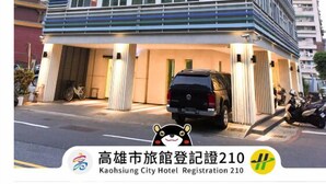 Ein modernes Hotelgebäude mit mehreren Etagen, großen Fenstern und einem Parkplatz mit einem schwarzen SUV.