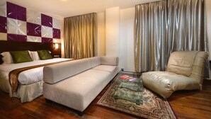 Ein Hotelzimmer mit Bett, Sofa, Sessel und einem Glastisch.