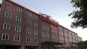 Ein mehrstöckiges Hotel mit roter Fassade und auffälligem Schild.