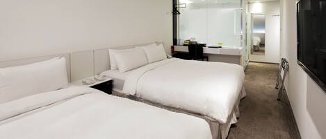 A hotel room with two beds, a desk, a chair, and a mirror.