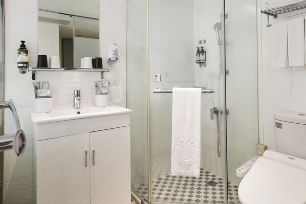 Uma casa de banho moderna com cabine de duche em vidro, lavatório branco e sanita.