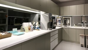 A modern kitchen with built-in appliances, a white countertop, and grey cabinetry.