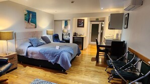 Una habitación de hotel moderna con una cama, un escritorio, una silla, una lámpara y un cuadro en la pared.