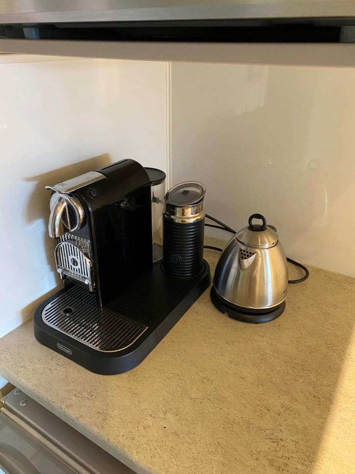 A coffee maker on a countertop next to a kettle.