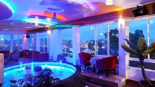 A modern lounge area with a pool, red chairs, and large windows offering a city view. - Thi Thao Gardenia Hotel (Xuan Huong - Da Lat)